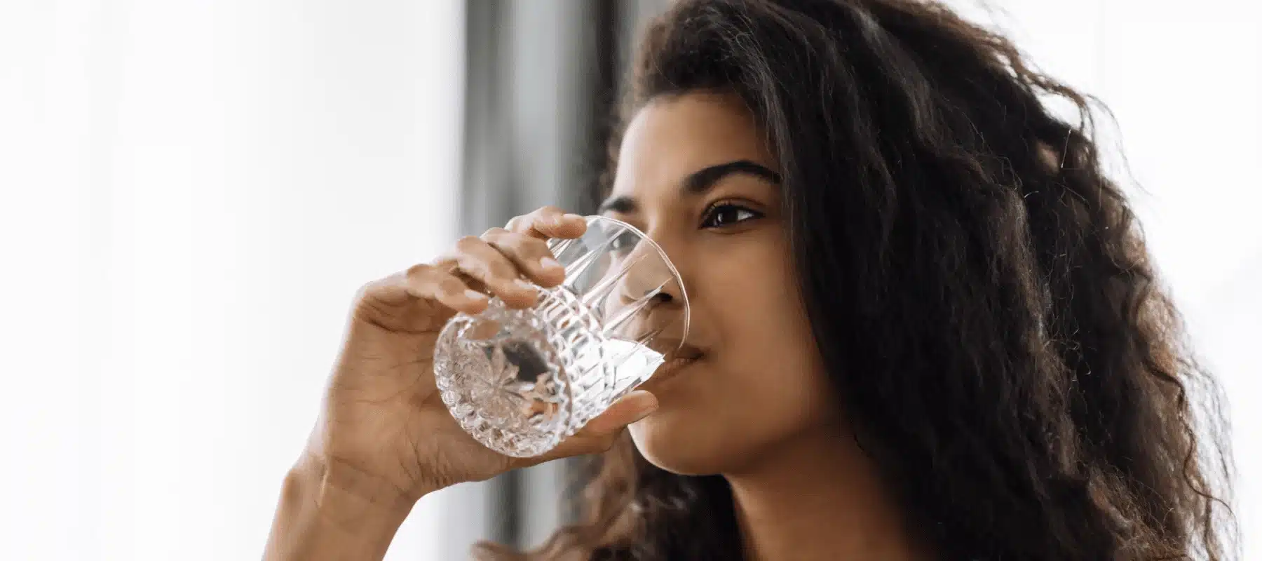 woman inside a home drinking clean water from a glass