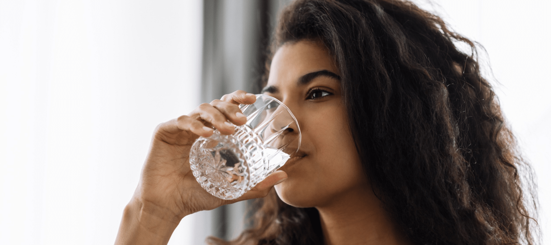 woman inside a home drinking clean water from a glass