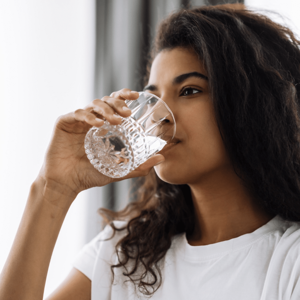 woman inside a home drinking clean water from a glass