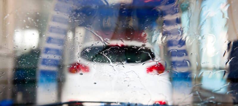 Blurry view of a car through a wet windshield inside an automatic car wash